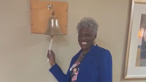 Dr. Joyce ringing bell signifying a cancer free diagnosis.
